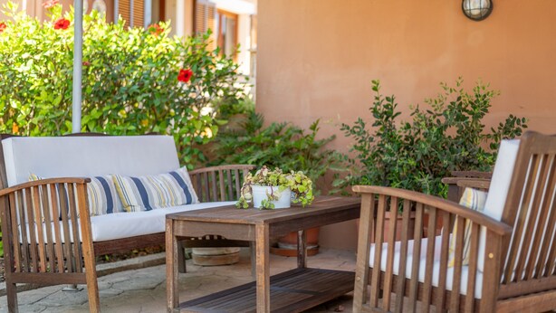 An outdoor seating area with a wooden table and two chairs, surrounded by potted plants and a sofa. - Holiday Home "Es Viola" with Mountain Views, Pool, Wi-Fi, Garden and Terrace (Santa Eugènia)