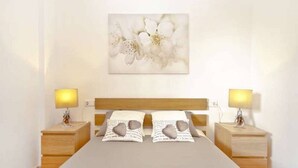Une chambre à coucher avec un lit, deux tables de chevet et une lampe fixée au mur.