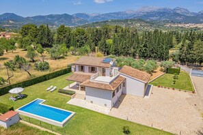 Una villa moderna con piscina, patio y vistas a las montañas.