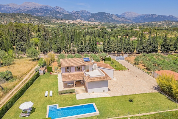 A house with a swimming pool, a patio, and a view of mountains.
