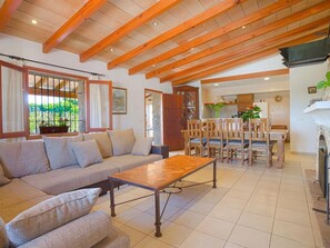 A living room with a sofa, coffee table, wooden beams, and a fireplace.