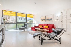A modern living room with a red sofa, a black lounge chair, a wooden coffee table, and a large window with yellow blinds. - Casa Sunny with Mountain Views, Wi-Fi, Air Conditioning, Garden and Terrace (Puerto de Soller)