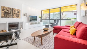 Una sala de estar moderna con un sofá rojo, una mesa de centro de madera, una chimenea y obras de arte en la pared.