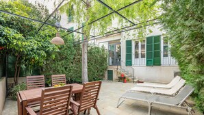 Un patio con una mesa y sillas de madera, una silla de descanso y un colgador de luz.