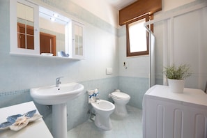 A bathroom with a sink, bidet, toilet, mirror, and a potted plant. - Vacation Home Villetta Relax Salento close to the Sea with Terrace & Garden (Torre Suda)