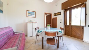 Ein Essbereich mit Tisch, Stühlen, einer Couch, einem Schrank und einer Tür.