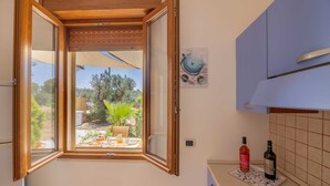 Eine Küche mit Fenster, einem Gasherd und zwei Flaschen auf der Arbeitsplatte.