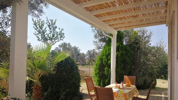 Eine Terrassengruppe im Freien mit Tisch für zwei Personen, umgeben von viel Grün und freiem Blick auf die Landschaft.