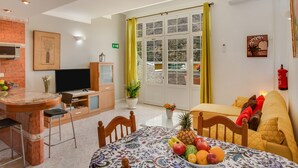 A well-lit room with a dining table, chairs, a TV, and a bed with pillows. - Apartment 'Casa Paco' with Mountain Views, Fast Wi-Fi, Air Conditioning and Terrace (Mogán)