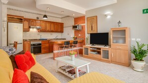 A modern kitchen with wooden cabinets, a built-in microwave, and a dining area with a white table and red cushions. - Apartment 'Casa Paco' with Mountain Views, Fast Wi-Fi, Air Conditioning and Terrace (Mogán)