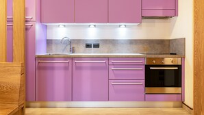 Una cocina con gabinetes morados, horno de acero inoxidable y un grifo moderno.