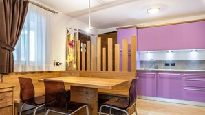 Una cocina moderna con armarios de madera y morado, una mesa de comedor de madera con sillas, y un lavamanos visible.