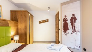 Habitación de hotel con cama, cabecero verde, armario de madera, lámpara de pared e imagen enmarcada.