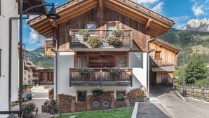 A wooden chalet with a balcony, a mountain view, and a rustic exterior.