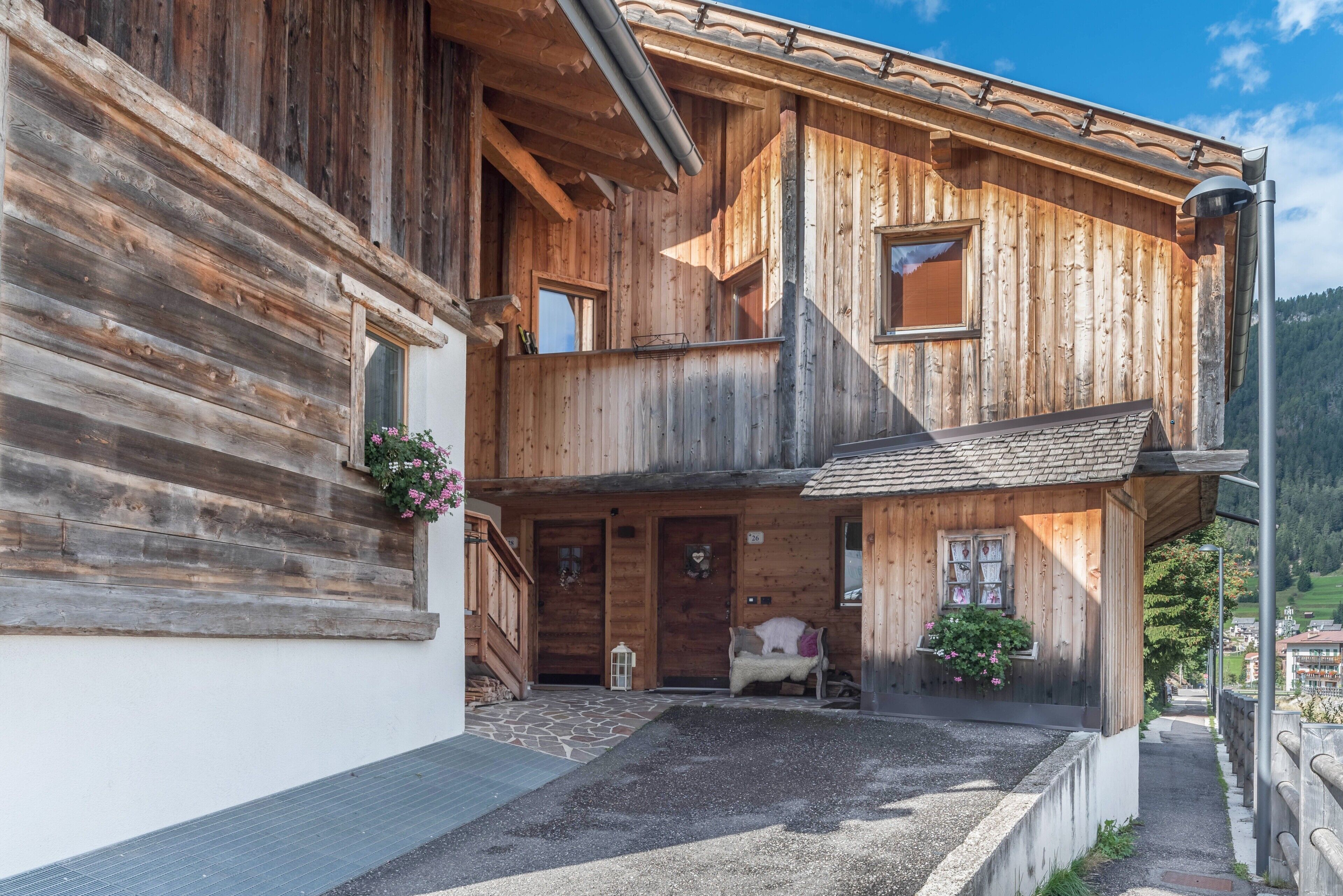 Un chalet de madera con balcón, un camino de piedra y un pequeño jardín.