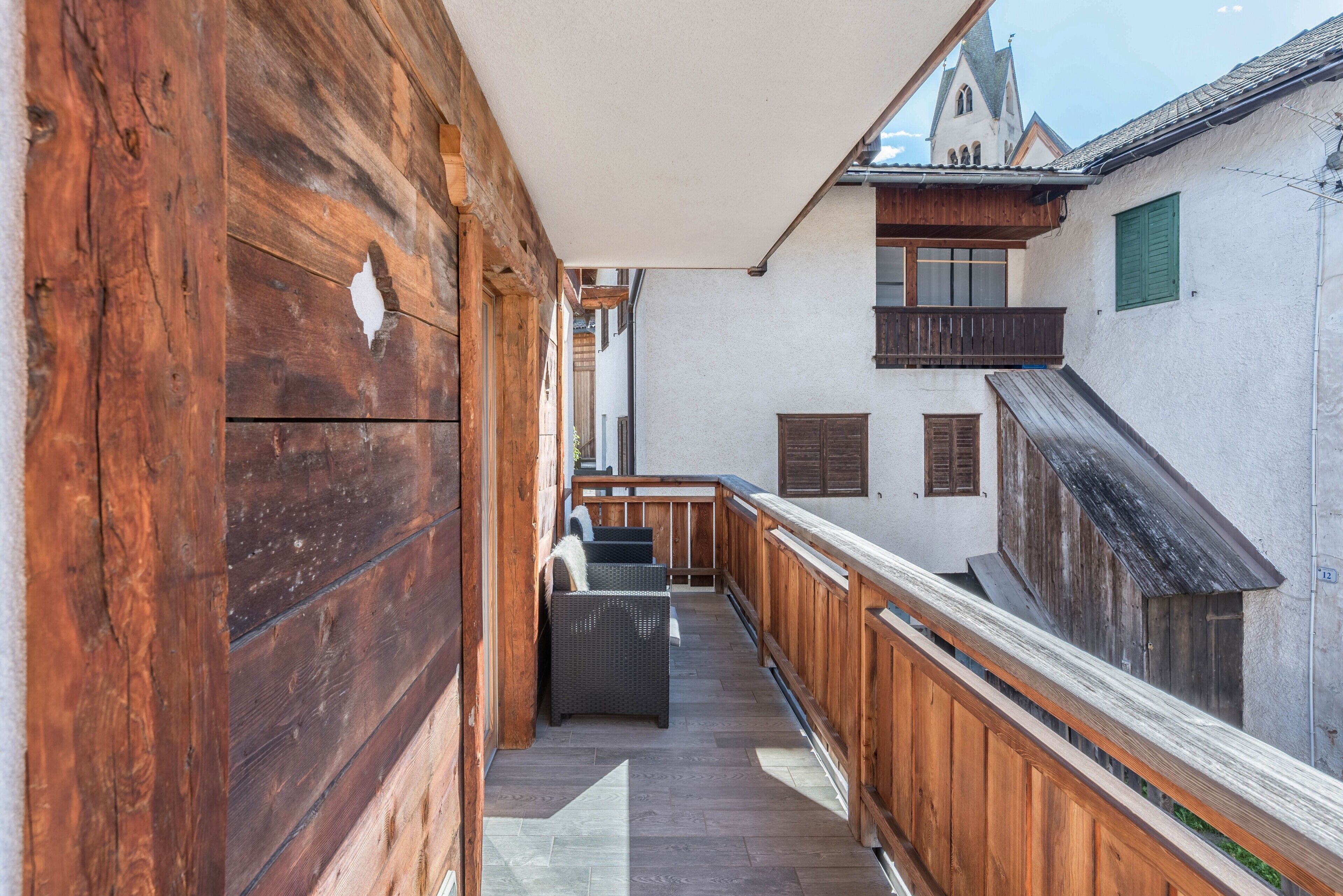 Ein Holzbalkon mit Blick auf eine Kirche und angrenzende Gebäude.