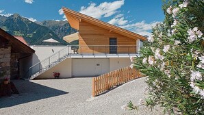 A modern chalet with a wooden facade, a balcony, and a view of mountains. - Vacation Apartment "Sauvignon" with Mountain View, Wi-Fi, Balcony, Terrace & Garden (Meran)