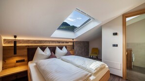 A bedroom with a skylight, a bed with pillows, a nightstand, and a wooden headboard. - Vacation Apartment "Barrique" with Mountain View, Wi-Fi and Garden (Meran)