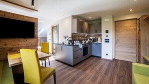 A modern kitchen with a central island, wooden accents, and a dining area with yellow chairs. - Vacation Apartment "Barrique" with Mountain View, Wi-Fi and Garden (Meran)