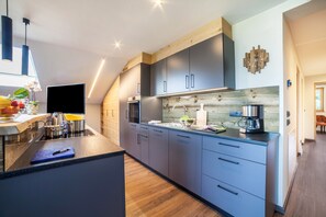 Une cuisine moderne dotée d’un îlot central, d’appareils électroménagers intégrés et d’un mur d’accent en bois.