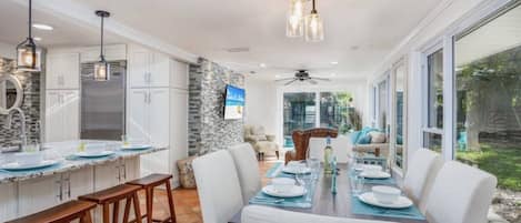 A modern kitchen with white cabinets, a built-in island, and bar stools.
