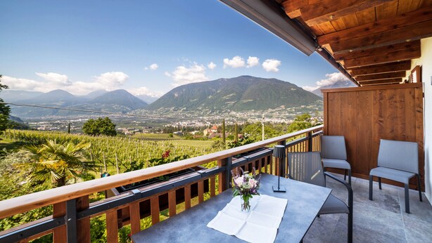 Un balcon avec une table, des chaises et un vase de fleurs.