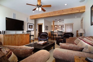 A living room with a television, leather chairs, a coffee table, and a dining area in the background. - Maison Carstens - Home easy access to ski run (Crested Butte)