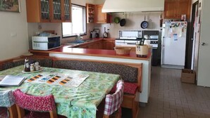 Una cocina con armarios de madera, una mesa de comedor con mantel floral y un refrigerador.