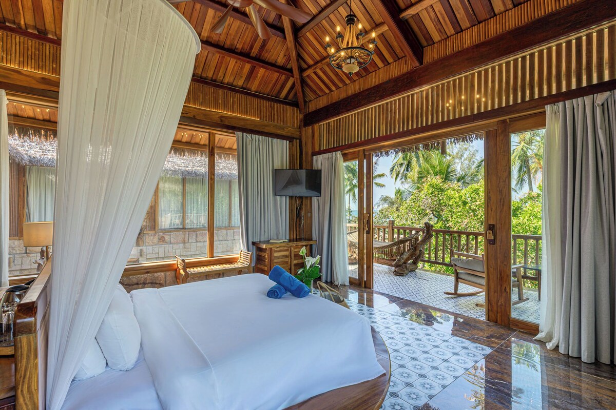 A bedroom with a bed, a TV, and a view of the outdoors.