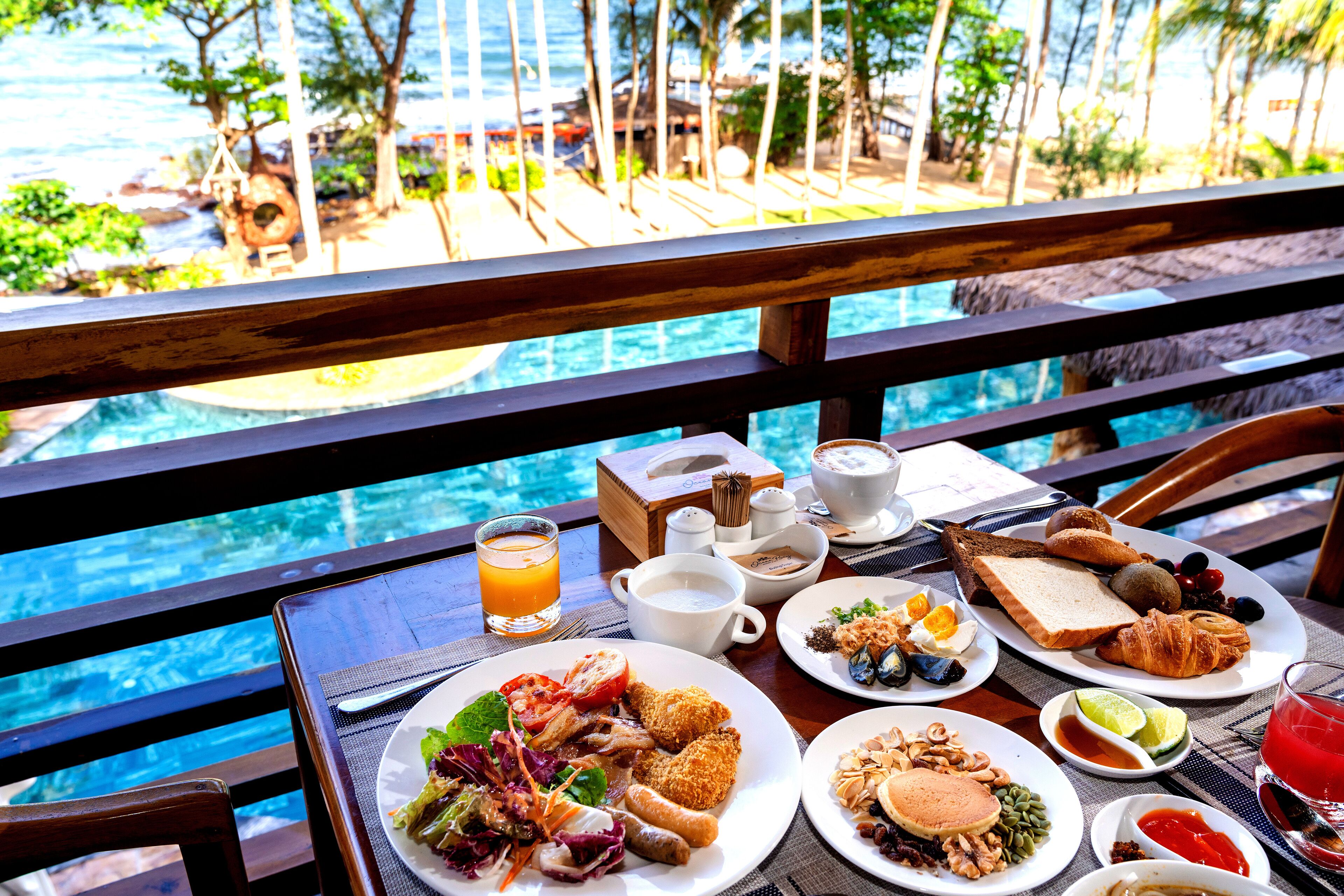 A dining table with breakfast items and a view of a pool.