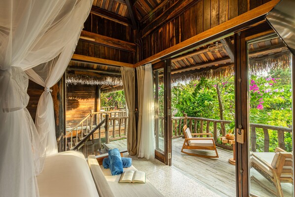 A wooden interior with a balcony, a sofa, a chair, and a book. - Ocean Bay Phu Quoc Resort and Spa (Phu Quoc)