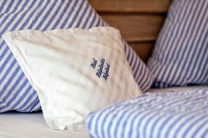 A bed with striped bedding and a white pillow with text.