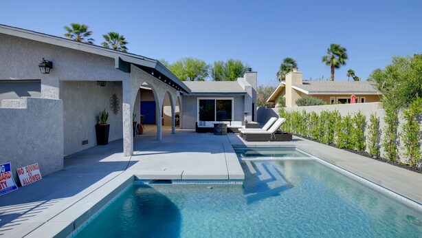 A modern house with a swimming pool, a covered patio, and a view of palm trees. - Theater Room & Pool Deck: Retreat in Palm Desert! (Palm Desert)