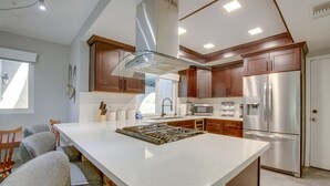 A modern kitchen with a central island, stainless steel appliances, and wooden cabinets. - Theater Room & Pool Deck: Retreat in Palm Desert! (Palm Desert)