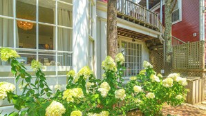 Une maison avec un balcon, un arbre et un jardin où poussent des hortensias.