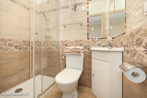 Une salle de bain avec une douche à parois de verre, des toilettes et un lavabo équipé d’un porte-serviettes.