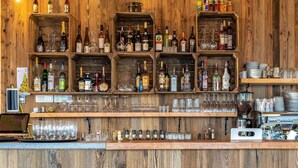 A bar area with wooden shelves stocked with various bottles and glasses. - Cozy Mountain Stay w/ Balcony (Arâches-La-Frasse)