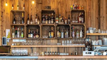 A bar area with wooden shelves stocked with various bottles and glasses.