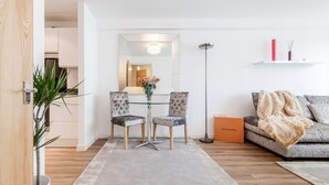 Una sala moderna con una mesa de comedor, dos sillas, un sofá, una lámpara de pie y una caja Louis Vuitton.