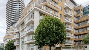 Un moderno edificio de apartamentos con balcones, un sendero pavimentado y un árbol.