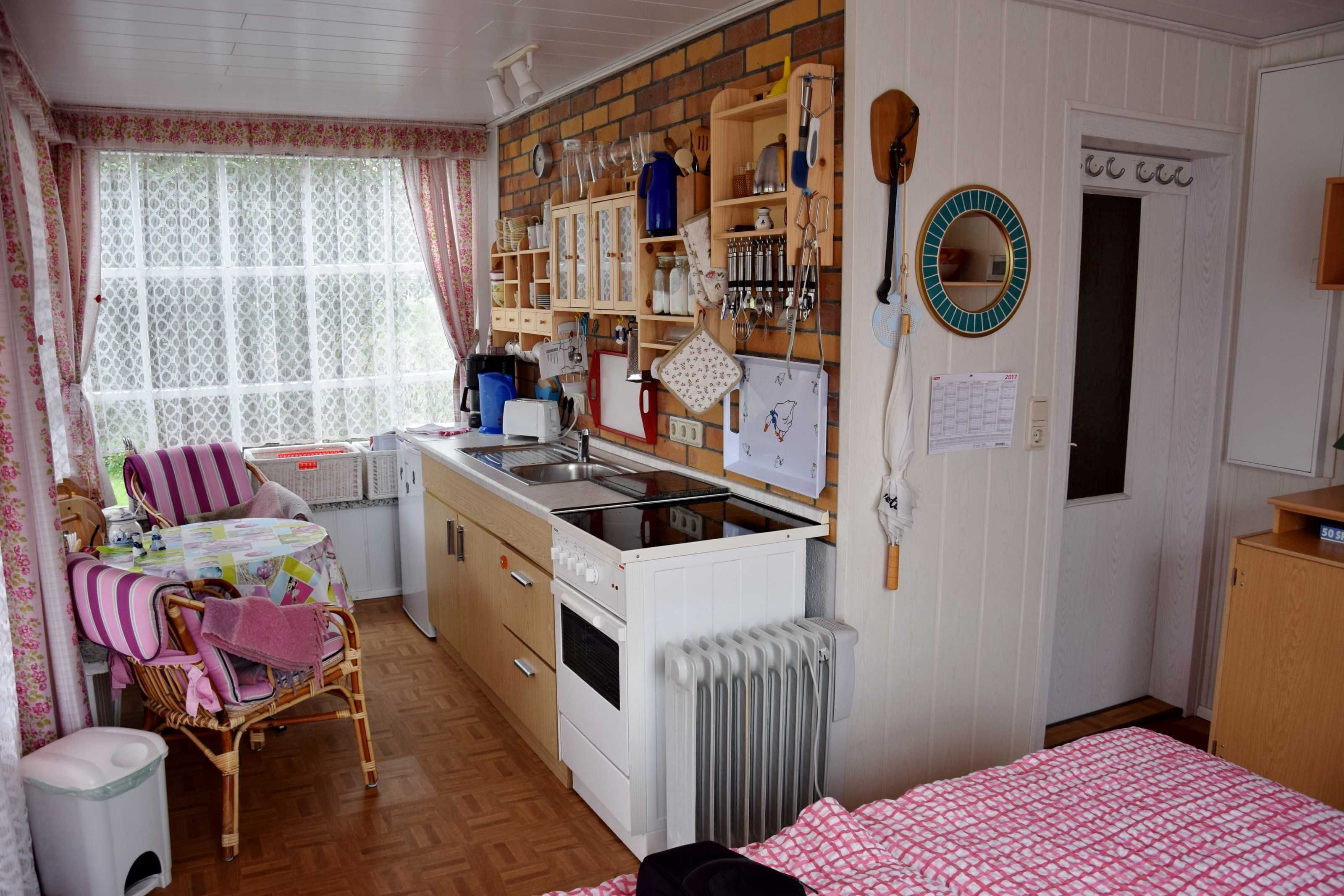 A cozy kitchen with wooden cabinets, a stove, and a dining area with wicker chairs and a table.