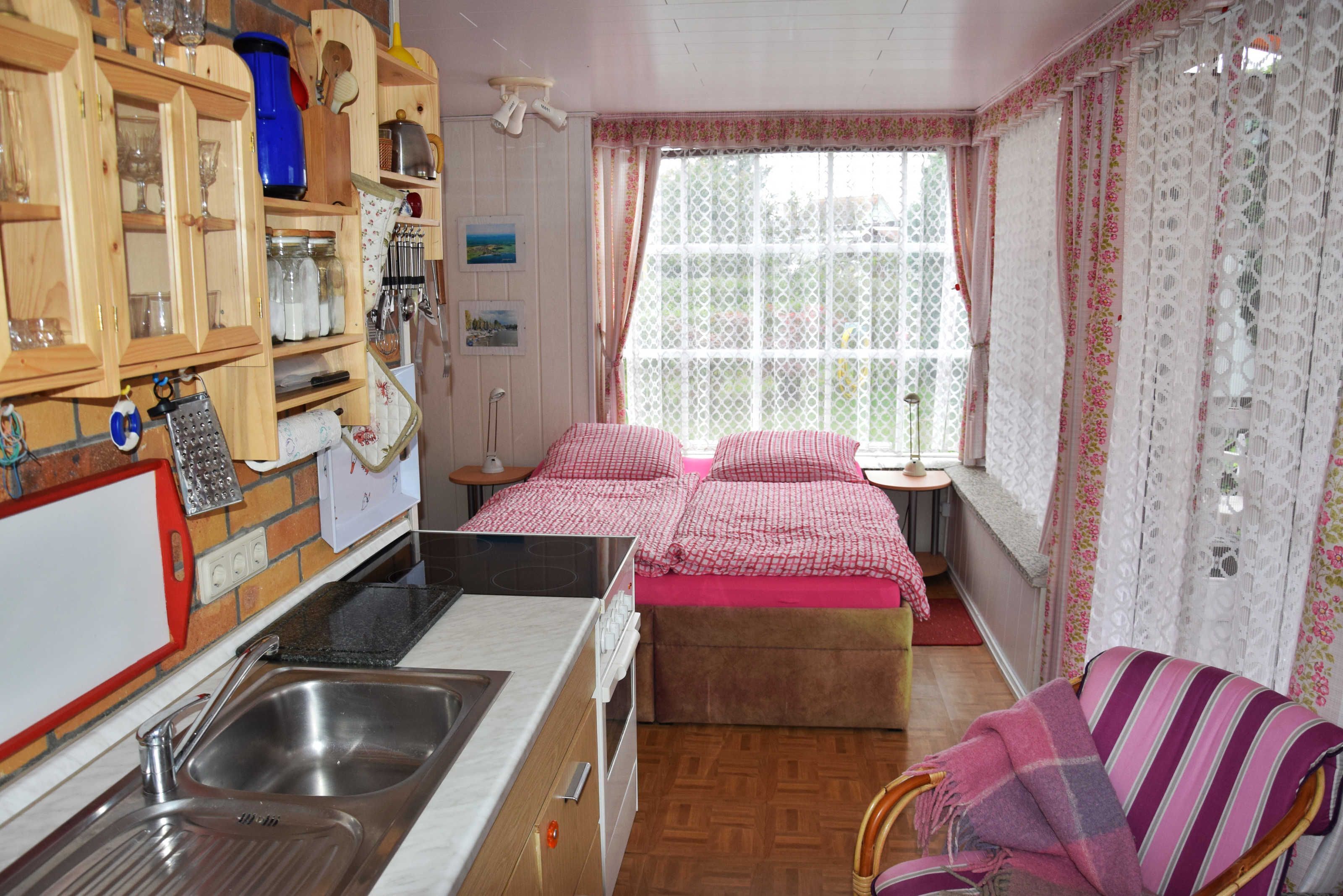 Ein gemütliches Schlafzimmer mit Bett, einem kleinen Nachttisch, einem Stuhl und einer Küchenzeile mit Spüle und Schränken.