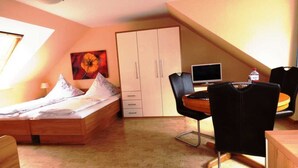 Une chambre à coucher avec un lit, un bureau avec un ordinateur, une chaise et une armoire.