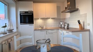 A modern kitchen with white cabinets, a built-in oven, a coffee maker, and a knife block.