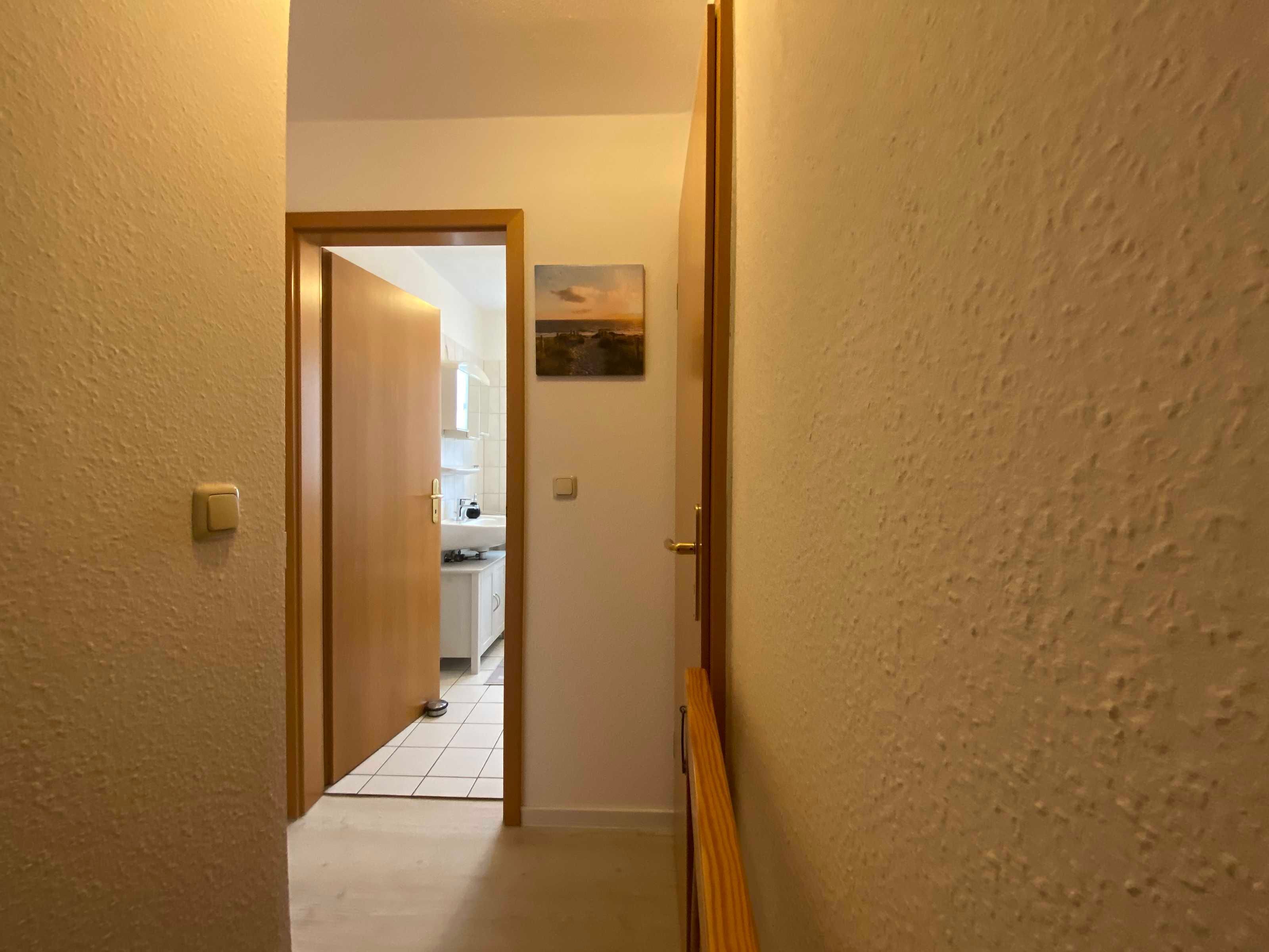 Un pasillo estrecho con una puerta que da a una zona de cocina.