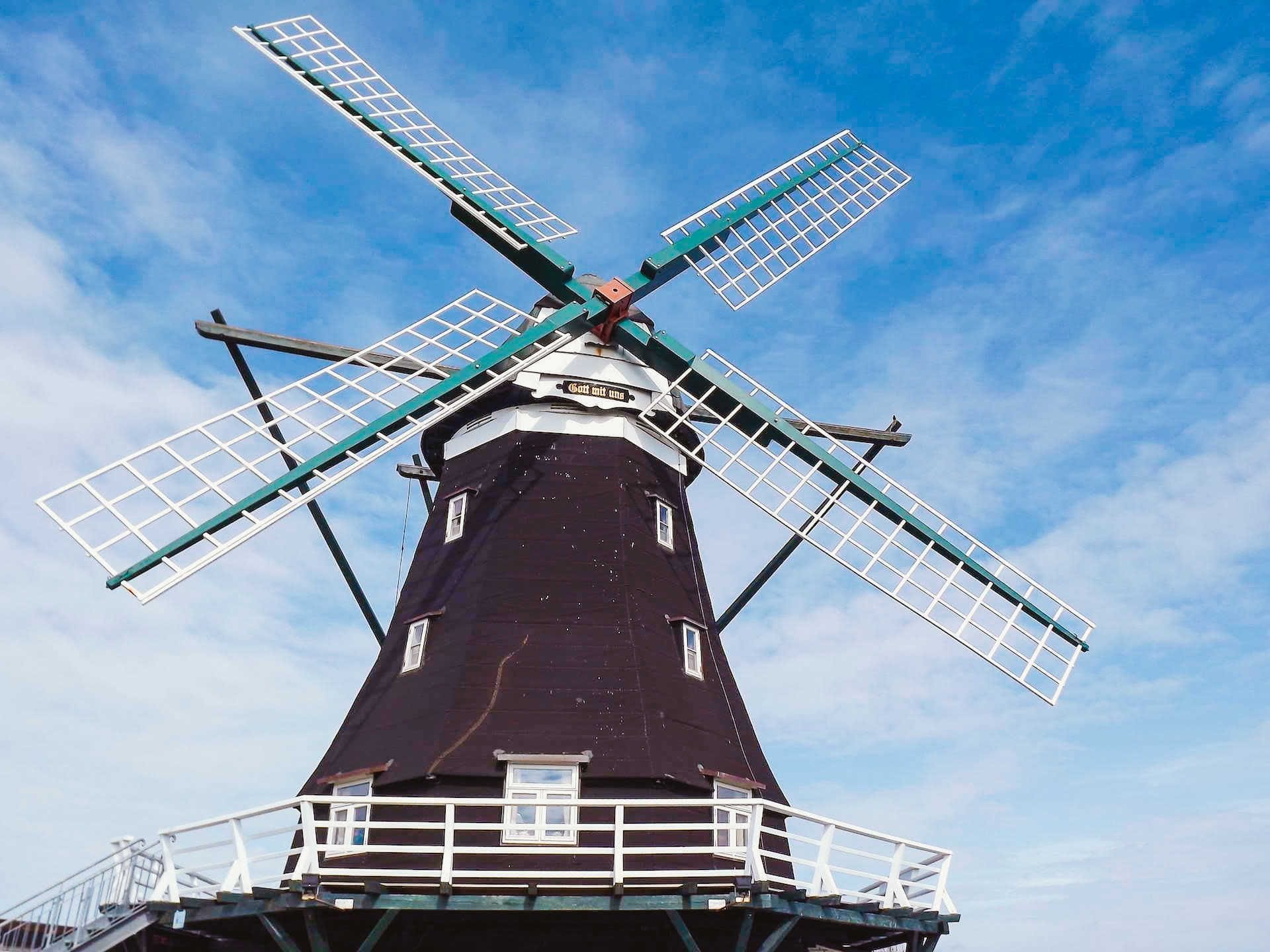 A windmill with a white balcony and a dark tower.