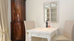 Een kamer met een houten kast, een tafel met een kant kleed, twee stoelen en een raam met een spiegel.