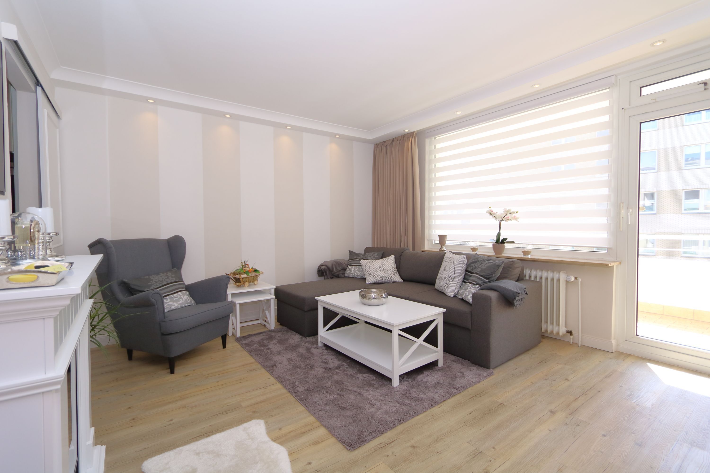 Ein modernes Wohnzimmer mit grauem Sofa, weißem Couchtisch und grauem Sessel.