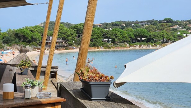 Eine Holzterrasse mit Blick auf Strand und Meer.