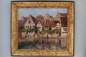 A framed painting of a riverside town with buildings and ducks. - The Little Window, Classic Cotswolds Cottage (Gloucestershire)